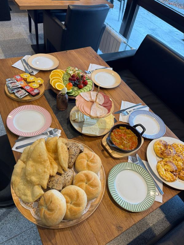 Gedeckter Tisch mit Brötchen, Aufschnitt und warmen Speisen im Familiencafé Zauberbaum