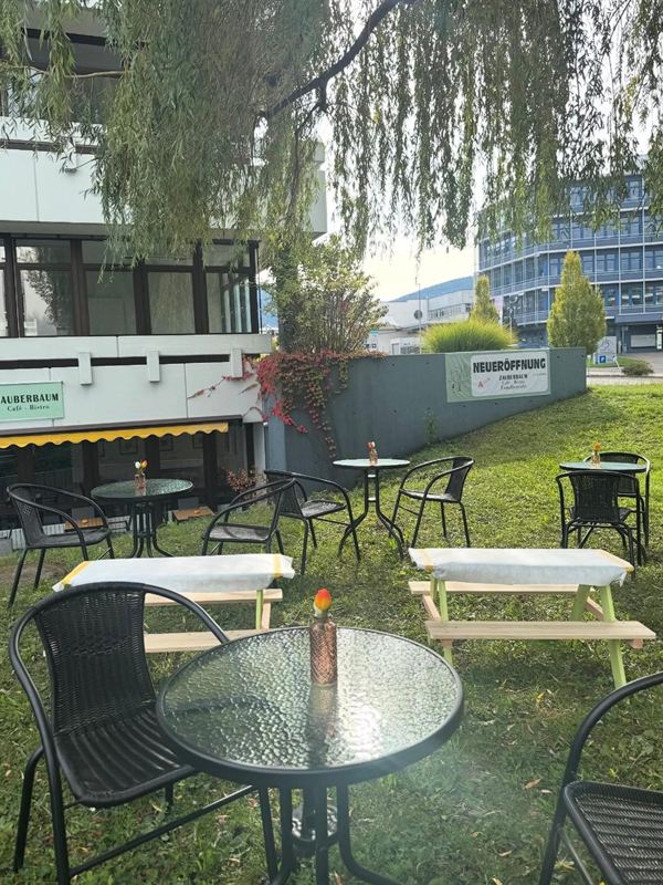 Terrasse mit Sitzgruppen unter der Trauerweide beim Familiencafé Zauberbaum in Eningen