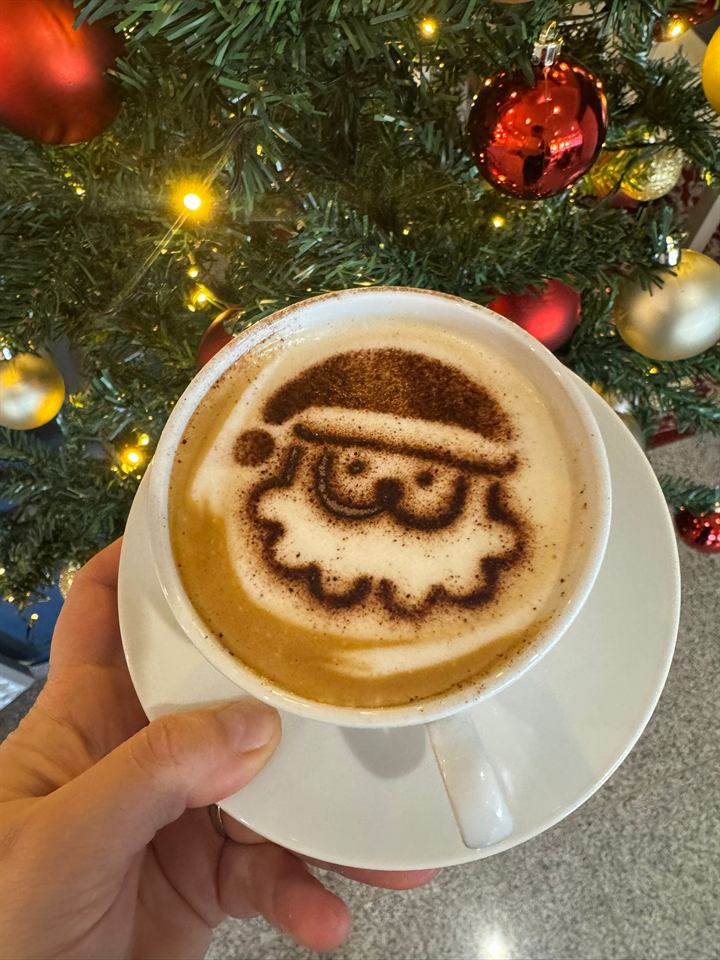 Cappuccino mit Nikolaus-Motiv vor dem Weihnachtsbaum im Café Zauberbaum