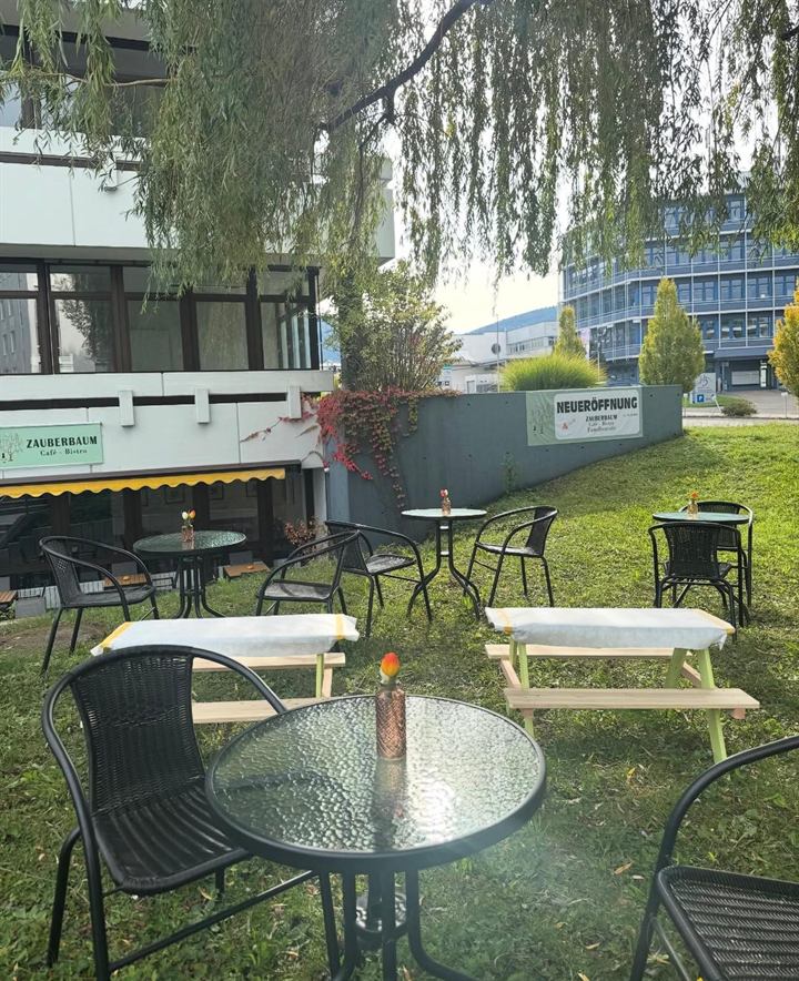 Gartenterrasse mit Tischen unter der Trauerweide beim Café Zauberbaum in Eningen